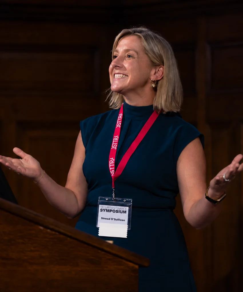 Sinead O'Sullivan laughing while gesturing, mid-sentence, hosting from the lectern